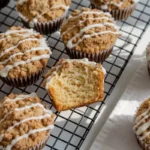 Freshly baked Cinnamon Streusel Muffins on a cooling rack, topped with crumbly streusel and white icing, illuminated by natural light